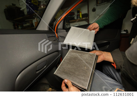 Replacing the air filter in the car interior A man holds in his hands an old and a new air filter from the inside of a car. The man shows how dirty the old filter is and how much dust there is in it. Replacing the air filter in the car interior A man holds in his hands an old and a new air filter from the inside of a car. The man shows how dirty the old filter is and how much dust there is in it. 112631001