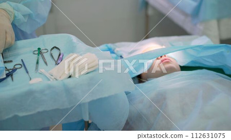 Close up the surgeon removes fat from the patient eyelid with special tools during blepharoplasty surgery. Surgical removal of the lower eyelid. 112631075