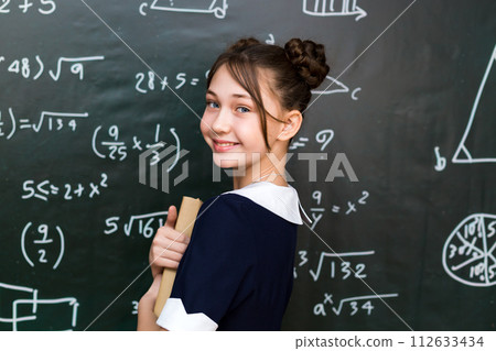 A schoolgirl girl with books and textbooks in her hands, a teenage girl 10-12 years old in a school class A schoolgirl girl with books and textbooks in her hands, a teenage girl 10-12 years old in a school class 112633434
