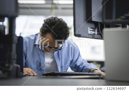 一名50多歲的男子在電腦顯示器前低著頭 112634697