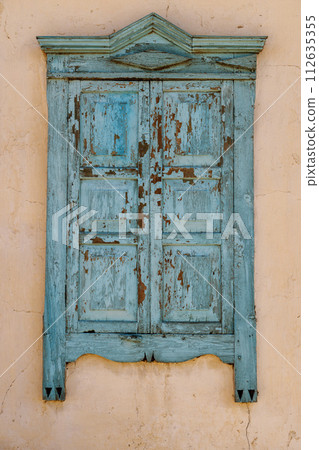 old wooden window with closed shutters on beige house wall old wooden window with closed shutters on beige house wall 112635355