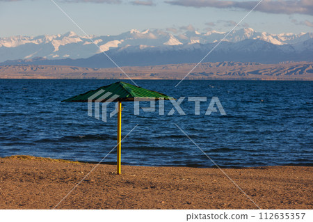 rigid steel umbrella on beach of mountain lake at sunny evening 112635357