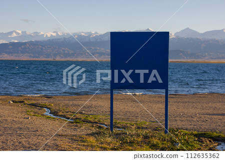 big blue sign on the beach of mountain lake at sunny afternoon 112635362