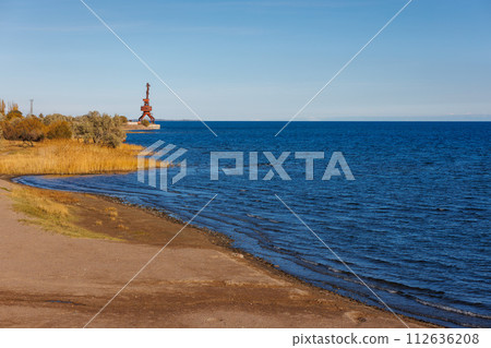 old rusted dock crane on mountain lake Issyk-Kul at sunny autumn afternoon 112636208