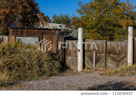 house with wooden kiosk overgrown with low shrub spiky caragana spinosa at sunny autumn afternoon 112636487