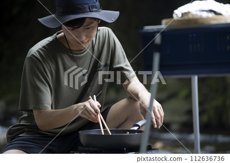 一名男子在煎鍋中煎炸食材的戶外影像 112636736