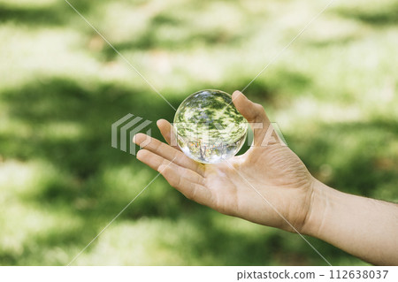 Close-up of hand holding transparent sphere at outdoors Close-up of hand holding transparent sphere at outdoors 112638037