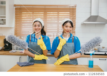 Cleaning service women in uniform stand on kitchen counter holding duster foggy spray and rag. Emphasizing teamwork in efficient housework. Clean portrait two uniform maid working smiling employee. Cleaning service women in uniform stand on kitchen counter holding duster foggy spray and rag. Emphasizing teamwork in efficient housework. Clean portrait two uniform maid working smiling employee. 112638583