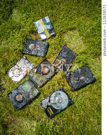 Burned hard drives lying on the green lawn 112639571