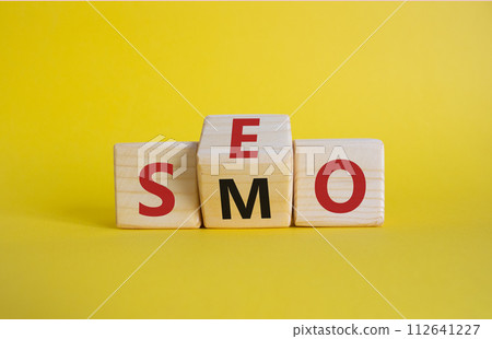 SEO vs SMO symbol. Wooden cubes with words SMO and SEO. Beautiful yellow background. SEO vs SMO and business concept. Copy space 112641227