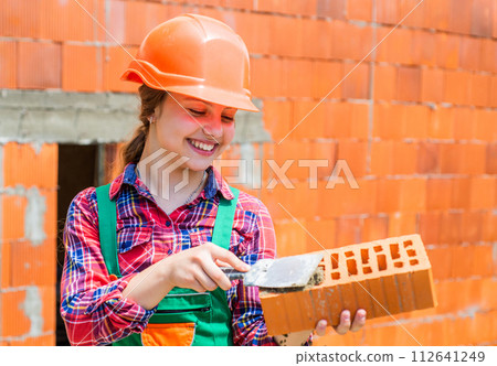 fascinating process. child is engineer architect. building her future house. happy childhood. kid wear protective helmet. protect head on construction site. girl hold brick. little builder with brick 112641249