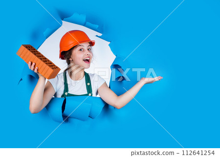 building a house. Kid build construction. engineer teen is construction worker. Professional craftsman or workman. International workers day. girl in helmet of builder with brick. presenting product 112641254
