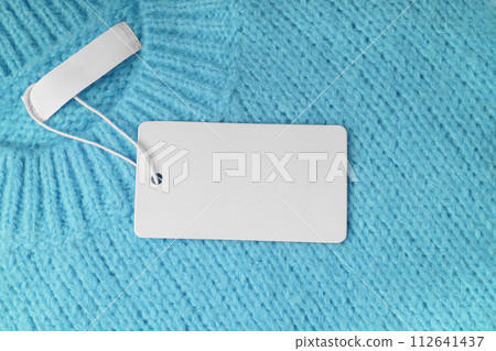 Blank clothing tag and inner label on neck of turquoise knitted sweater background 112641437
