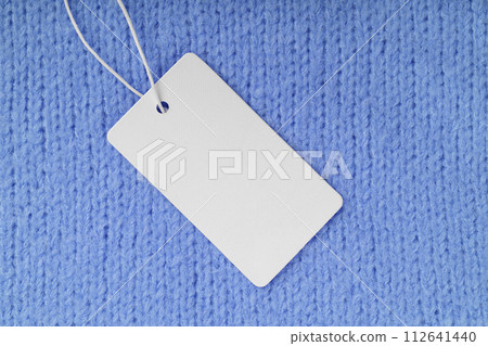 Template of blank clothing label, price tag on blue knitted sweater background 112641440