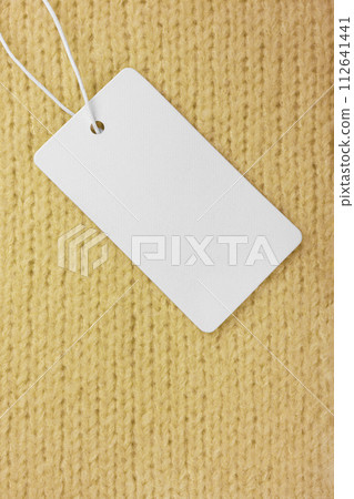 Template of blank clothing label, price tag on yellow knitted sweater background 112641441