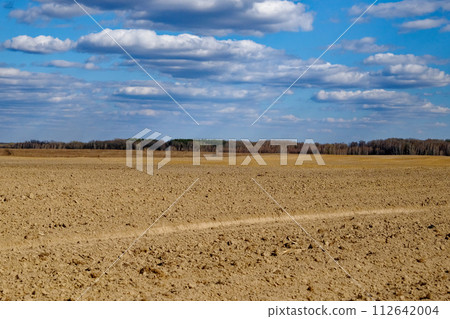 Open farmland with rich soil and a cloud-filled sky. 112642004