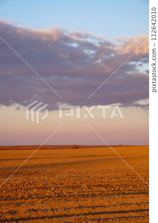 The image captures rocks on ground with clouds in the distant sky. 112642010
