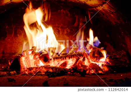 A dynamic display of flames engulfs the wood in a fiery dance. 112642014