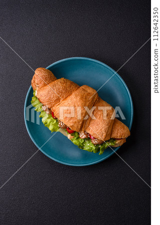 Delicious fresh crispy croissant with chicken or beef meat, lettuce, tomatoes, spices and sauce 112642350