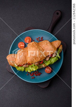 Delicious fresh crispy croissant with chicken or beef meat, lettuce, tomatoes, spices and sauce 112642366
