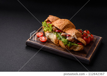 Delicious fresh crispy croissant with chicken or beef meat, lettuce, tomatoes, spices and sauce Delicious fresh crispy croissant with chicken or beef meat, lettuce, tomatoes, spices and sauce 112642367
