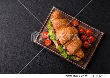 Delicious fresh crispy croissant with chicken or beef meat, lettuce, tomatoes, spices and sauce Delicious fresh crispy croissant with chicken or beef meat, lettuce, tomatoes, spices and sauce 112642368