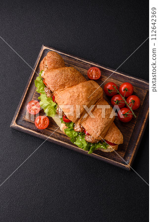 Delicious fresh crispy croissant with chicken or beef meat, lettuce, tomatoes, spices and sauce Delicious fresh crispy croissant with chicken or beef meat, lettuce, tomatoes, spices and sauce 112642369