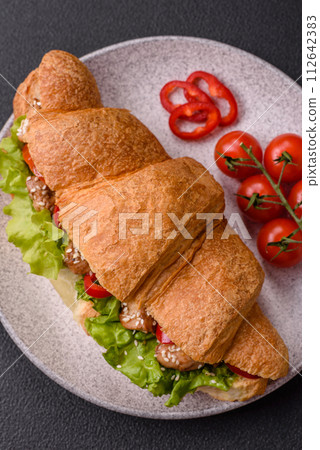 Delicious fresh crispy croissant with chicken or beef meat, lettuce, tomatoes, spices and sauce 112642383