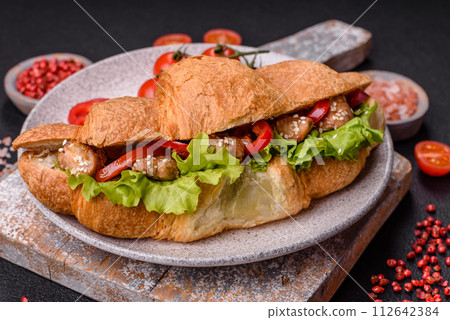 Delicious fresh crispy croissant with chicken or beef meat, lettuce, tomatoes, spices and sauce Delicious fresh crispy croissant with chicken or beef meat, lettuce, tomatoes, spices and sauce 112642384