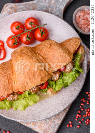 Delicious fresh crispy croissant with chicken or beef meat, lettuce, tomatoes, spices and sauce 112642385