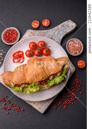 Delicious fresh crispy croissant with chicken or beef meat, lettuce, tomatoes, spices and sauce 112642388
