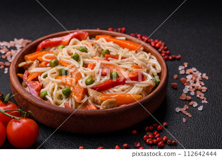 Delicious rice noodles or udon with chicken, carrots, pepper, salt, spices and herbs 112642444