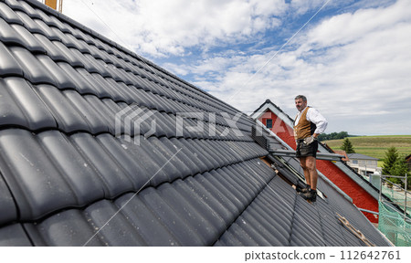 roofer working with tiles on the roof. roofer working with tiles on the roof. 112642761