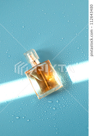 Perfume woman bottle on blue background with hard light and water drops. with shadows flat lay, top view 112643480