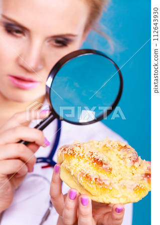 Doctor with magnifying glass examining sweet food 112643930