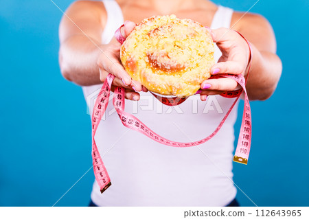 Woman holds sweet bun recommending non sugar diet 112643965