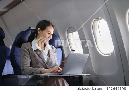 Asian female using laptop computer and holding credit card in airplane, Business traveling and technology concept. 112644198