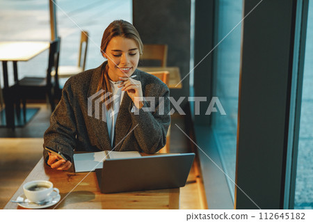 Pretty woman manager working on laptop while sitting in cozy cafe. High quality photo 112645182