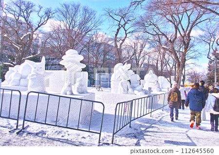 Sapporo Snow Festival with blue skies visible, tourists walking through Odori Park lined with small snow statues Sapporo Snow Festival with blue skies visible, tourists walking through Odori Park lined with small snow statues 112645560
