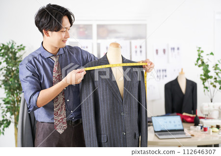 Young male stylist measuring size with a tape measure Young male stylist measuring size with a tape measure 112646307