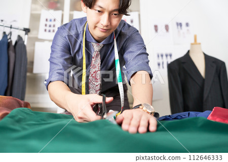 A young clothing designer working with scissors A young clothing designer working with scissors 112646333