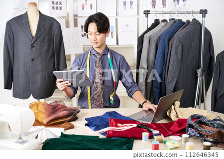 A young clothing designer works while looking at a tablet 112646345