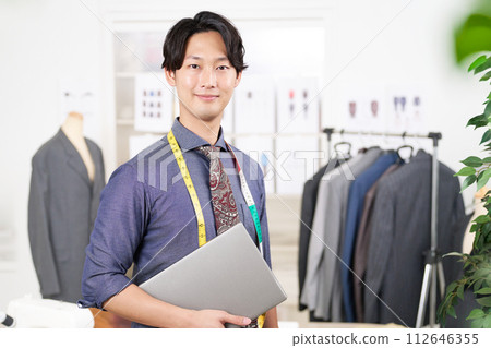 服裝設計師拿著筆記型電腦看著別處 112646355