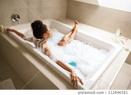 Woman enjoying a leisurely bath in a foamfilled bathtub Woman enjoying a leisurely bath in a foamfilled bathtub 112646381