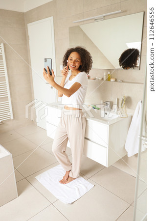 A woman in the bathroom taking a selfie with her phone 112646556