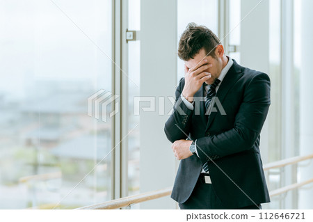 穿著西裝的外籍商人擔心車站、航廈或大樓出現麻煩（思考、擔心、遇到麻煩） 112646721