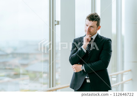 穿著西裝的外國商人在車站、航站樓或大樓裡雙臂交叉（思考、擔心、遇到麻煩） 112646722