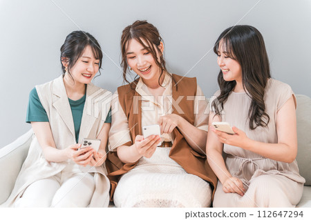 Women, friends, mom friends, and colleagues who use smartphones together at home 112647294