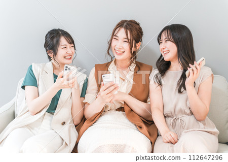 Women, friends, mom friends, and colleagues who use smartphones together at home Women, friends, mom friends, and colleagues who use smartphones together at home 112647296