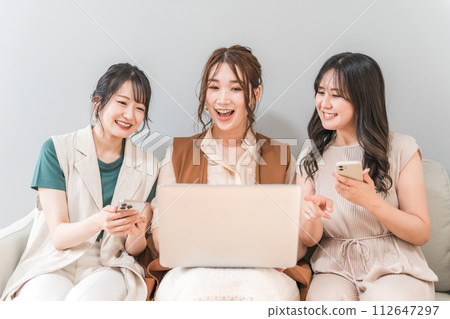 Women, friends, mom friends, and colleagues who use smartphones and laptops together at home 112647297